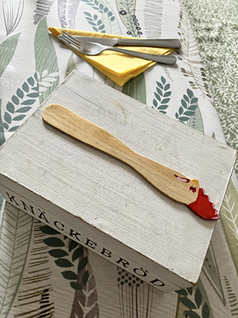 Påskdukat med gula servetter bestick smörkniv med tuppkam på låda för knäckebröd Påskdukat med gula servetter bestick smörkniv med tuppkam på låda för knäckebröd