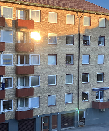 Solen speglas i ett fönster i huset mitt emot