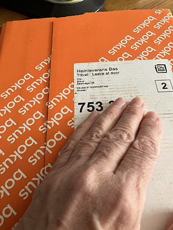 Min hand på orange paket från Bokus