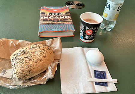 Jobblunch med macka kokt ägg varm choklad vatten o boken Förbjuden ingång