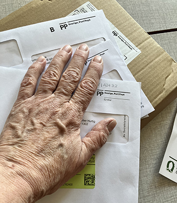 Fönsterkuvert och brunt paket med min hand på