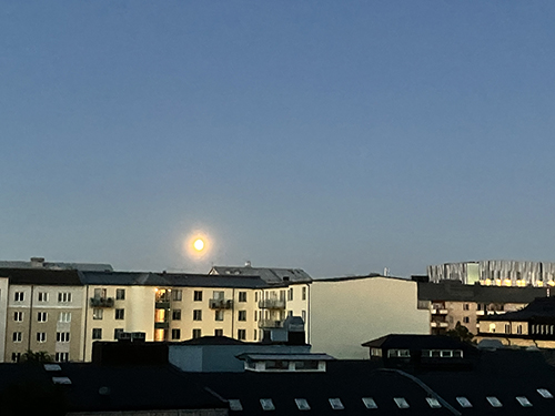 Måne över hustaken halv två natten till 25 juni 2024