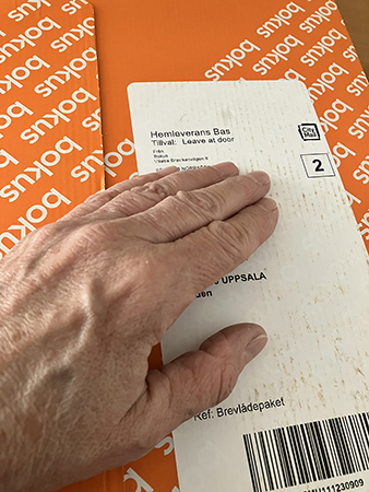 Orange paket från Bokus med min hand på