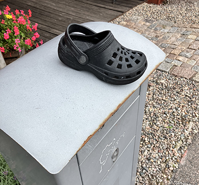 Svart barnfoppatoffel på brevlåda Svart barnfoppatoffel på brevlåda