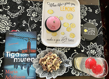 Gin oclock med boken Tiga som muren och en skål blandade nötter Gin oclock med boken Tiga som muren och en skål blandade nötter