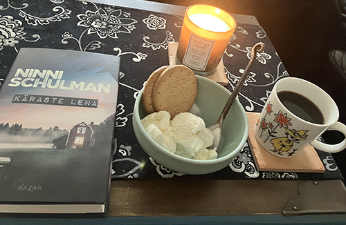 Kvällskaffe med glass digestive tänt ljus o boken Käraste Lena