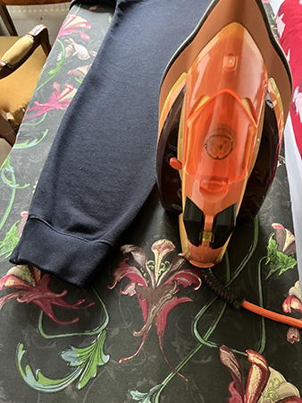 Orange strykjärn på strykbräda med tröja