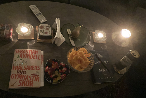 Vardagsrumsbordet med böckerna Frälsarens nya gymnastikskor o En bättre man ostbågar godis o en öl