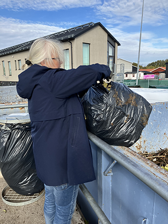 Anna slänger trädgårdsavfall på återvinningscentralen