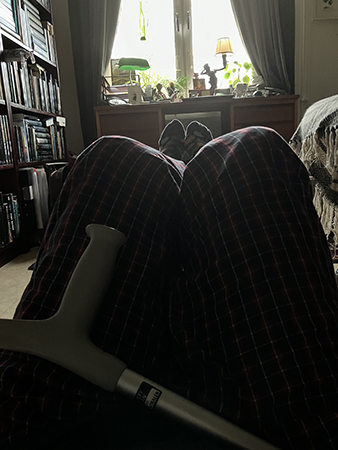 På golvet med benen på fotpall i rutiga pyjamasbyxor