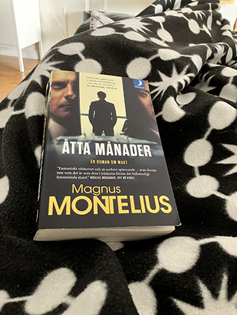 På soffan under filt med boken Åtta månader