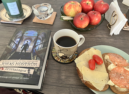 Boken Drottningen kaffe o smörgås på vardagsrumsbordet