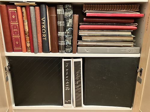 Album inte genomgångna i hylla bakom dörrar