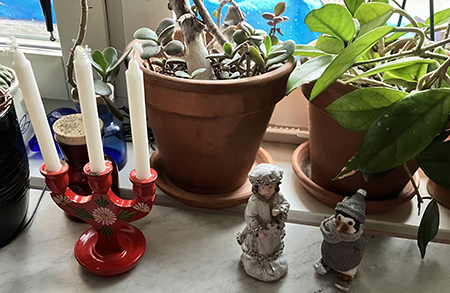 En liten trästake och ett par julfigurer i köksfönstret