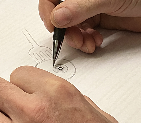 Bänkgrannen ritar en ögonglob med en gaffel i