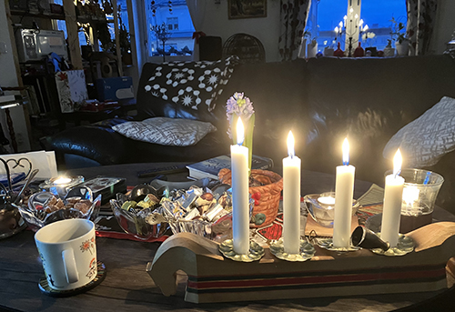 Kaffemugg godisskålar och fyra ljus tända i adventsljusstaken