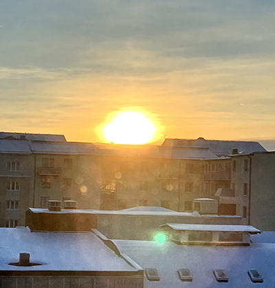 Stor januarisol går upp bakom husen på baksidan