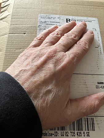 Min hand på ett brunt paket