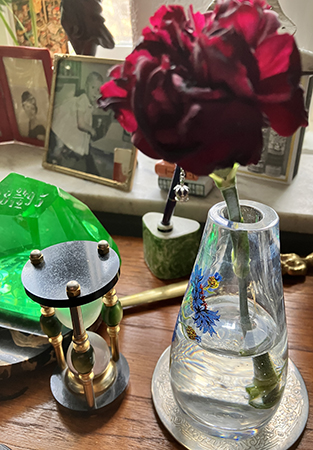 Röd avklippt nejlika i liten vas på skrivbordet