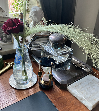 Röd nejlika o gräs i liten vas på skrivbordet