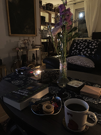 Kvällskaffe med bok och fullmåne som lyser in genom balkongdörren