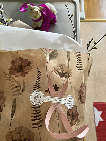 Köksgrisen med lila rosett och blompaket med ris o vide från Nya Björck blomsterhandel