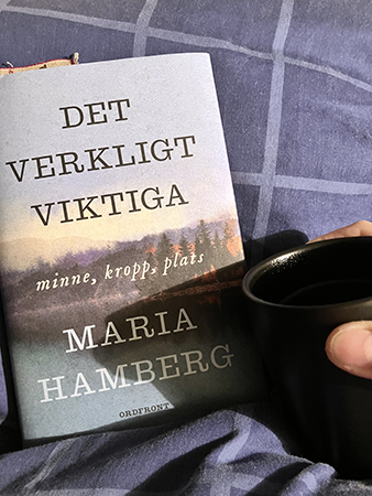 Läser Det verkligt viktiga och dricker kaffe på sängen