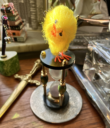 Påskkyckling på timglaset på skrivbordet