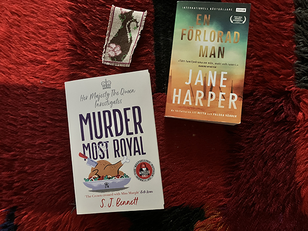 Böckerna Murder most royal och En förlorad man broderat kattbokmärke på pappas ryamatta