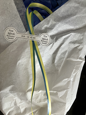 Blommor i silkespapper och blågult snöre