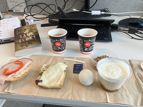 Jobblunch vid skrivbordet med Sandslott macka ägg yoghurt varm choklad Jobblunch vid skrivbordet med Sandslott macka ägg yoghurt varm choklad
