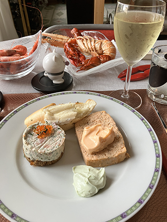 Skaldjursfest med laxbakelse o skaldjurspaté på tallriken räkor kräftor havskräfta riesling