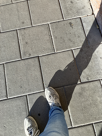 Mina jeansben och fötter på gråa plattor på väg till jobbet