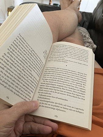 Bokupslag på shortsben i soffan