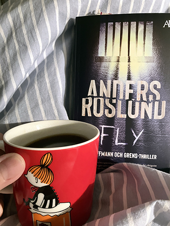 Lilla Mymugg med kaffe på sängen och boken Fly