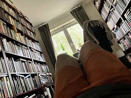 På golvet i arbetsrummet med shortsbenen upp på en pall