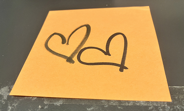 Två svarta hjärtan på orange papper