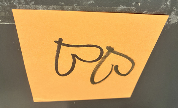 Två svarta uppochnervända hjärtan dvs stjärtar på orange papper Två svarta uppochnervända hjärtan dvs stjärtar på orange papper