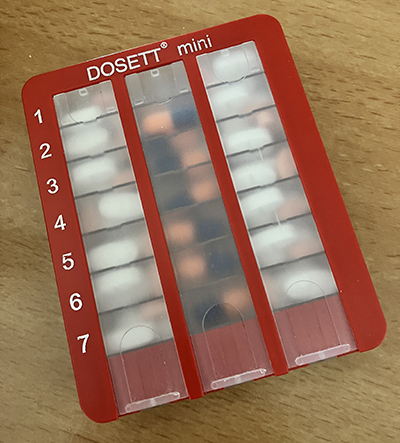 Knökfylld dosett med mediciner för en vecka