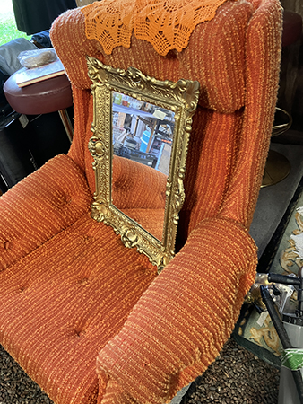 Orange fåtölj med orange virkade dukar och spegel med guldram Loppismagasinet
