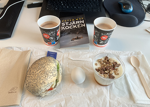 Skrivbordslunch med boken Stjärnkocken mellan två muggar choklad