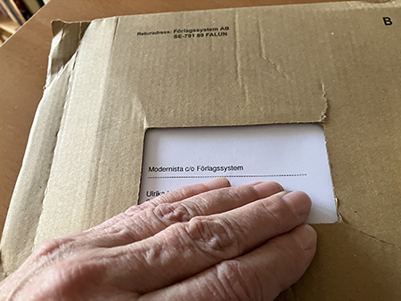 Bokpaket från Modernista med min hand på okt 2025