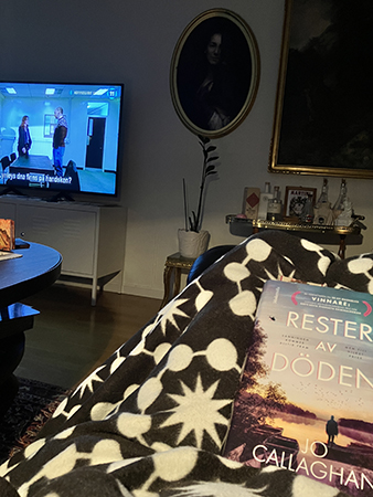 På soffan i vardagsrummet med TVn på filt o bok i knäet