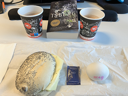 Skrivbordslunch på jobbet med macka ägg varm choklad o boken Isberg