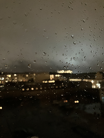 Regn på vardagsrumsfönstret och mörk himmel
