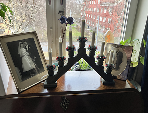 Blå adventssljusstake på sekretären i gästrummet mellan två bröllopsfoton föräldrar o farföräldrar
