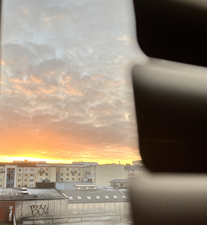 Soluppgång bakom husen foto bakom persiennen