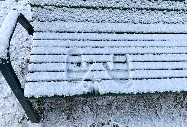 Snöig bänk med avtryck av två händer med vantar nyårsafton 2025