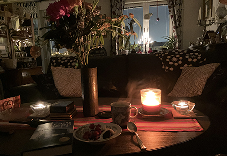 Dessert och kaffe i vardagsrummet med nyårsbukett och levande ljus