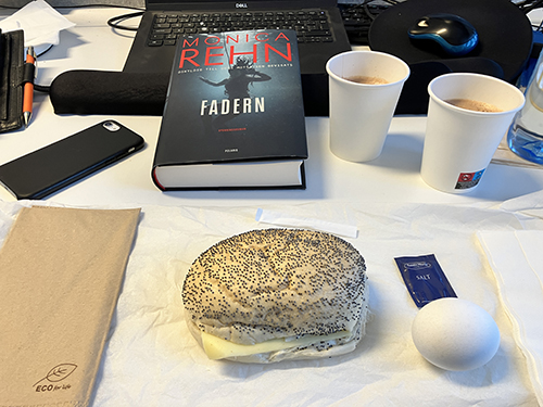 Skrivbordslunch med macka ägg varm choklad och Fadern